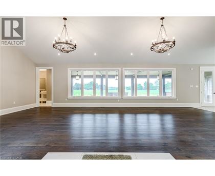 A spacious room with wooden floors and two chandeliers.