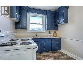 A kitchen with a white stove top oven and blue cabinets.