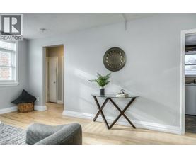 A living room with a grey sofa, a wooden coffee table, and a round mirror on the wall.