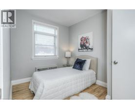 A bedroom with a white bed and a picture on the wall.