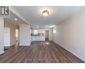 A spacious room with wooden flooring and white walls.