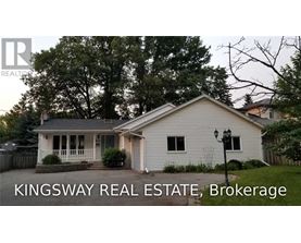 A white house with a porch and a sign that says Kingsway Real Estate Brokerage.