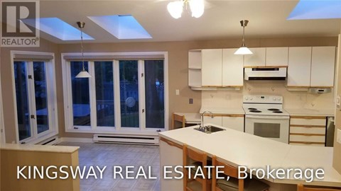 A kitchen with a skylight and a stove top oven.