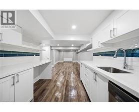 A modern kitchen with white cabinets and a wooden floor.