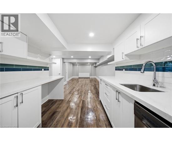 A modern kitchen with white cabinets and a wooden floor.