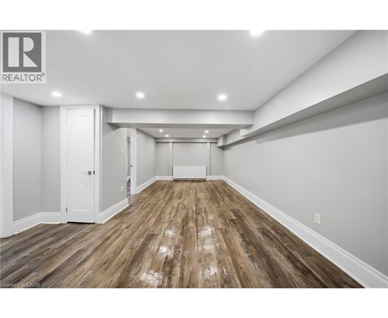 A spacious room with wooden flooring and white walls.