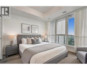 A bedroom with a large bed, a nightstand with a lamp, and a window with a view.