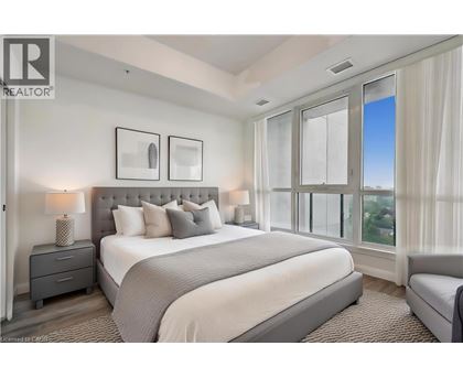 A bedroom with a large bed, a nightstand with a lamp, and a window with a view.