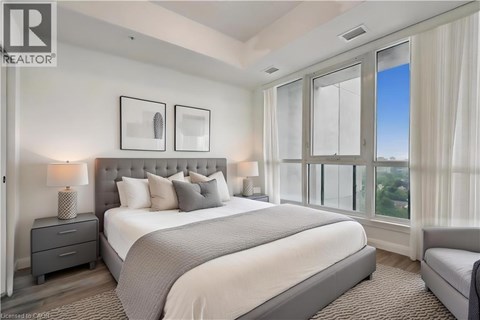 A bedroom with a large bed, a nightstand with a lamp, and a window with a view.