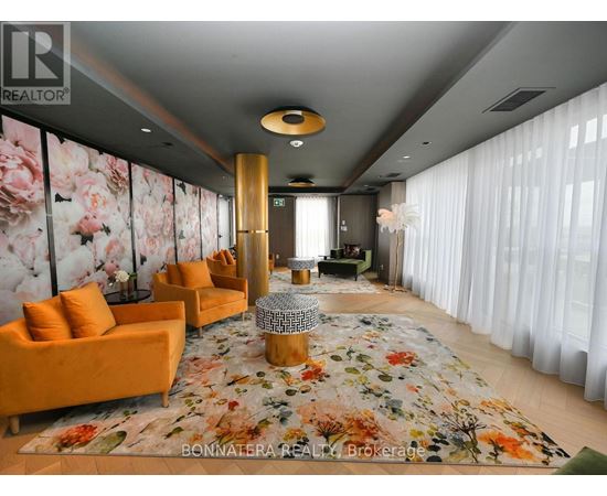 A living room with orange chairs and a floral rug.
