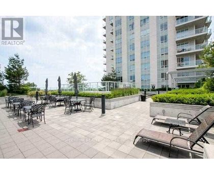 A patio area with tables and chairs is in front of a tall building.