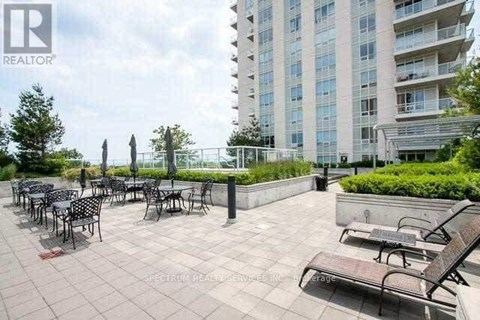 A patio area with tables and chairs is in front of a tall building.