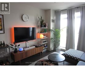 A living room with a flat screen TV, a coffee table, and a potted plant.