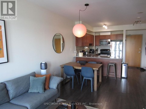 A living room with a grey couch and a dining table with blue chairs.