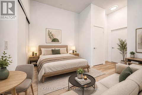 A bedroom with a bed, a chair, a table, and a couch.