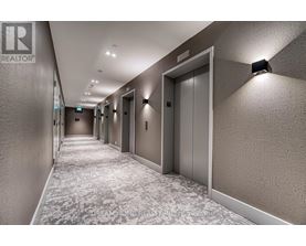 A hallway with elevators on the right side and a REALTOR sign on the wall.