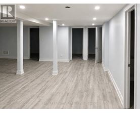 A long hallway with white walls and wood flooring.
