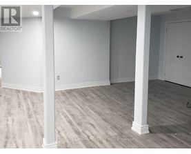A room with white pillars and grey carpet.