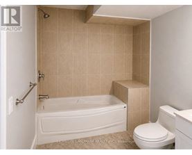 A bathroom with a white tub and tiled walls.