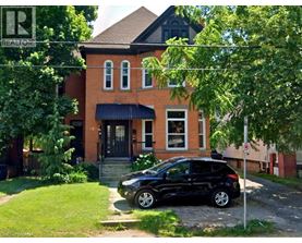 A black car is parked in front of a red brick house.