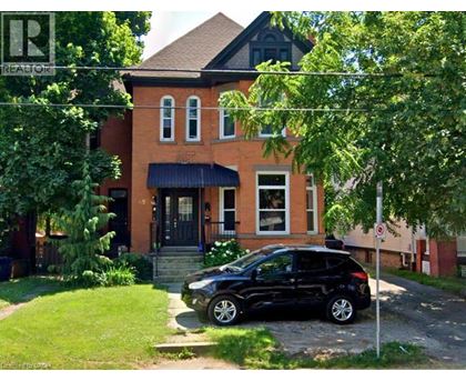 A black car is parked in front of a red brick house.
