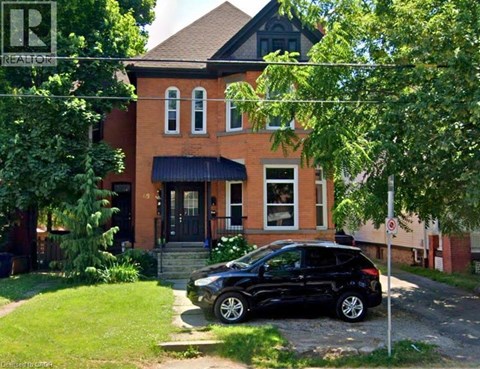 A black car is parked in front of a red brick house.