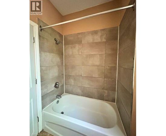 A white bathtub in a bathroom with beige tiles.