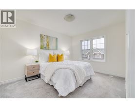 A bedroom with a large bed and a painting on the wall.
