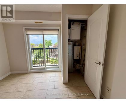 A room with a sliding glass door leading to a balcony and a kitchen area with a refrigerator, sink, and cabinets.