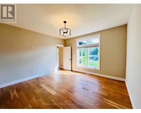 A room with wooden flooring and a window with a view of trees.