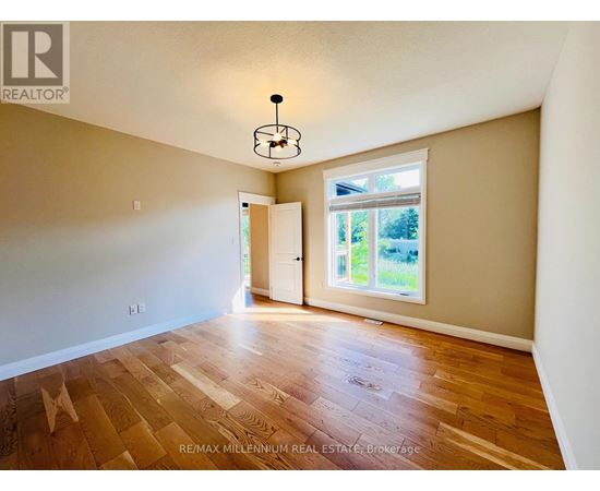 A room with wooden flooring and a window with a view of trees.