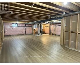A spacious room with wooden flooring and exposed ceiling beams.