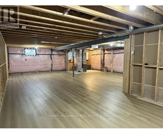 A spacious room with wooden flooring and exposed ceiling beams.