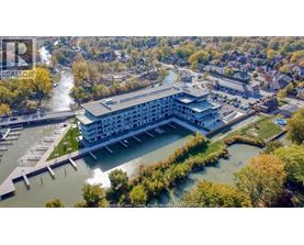 A large building with a waterfront is surrounded by trees.