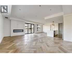 A spacious room with wooden flooring and a large window.