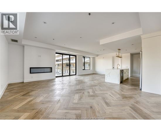 A spacious room with wooden flooring and a large window.