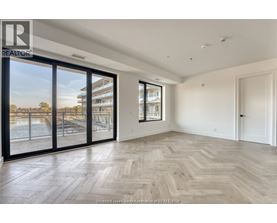A spacious room with wooden flooring and large windows overlooking a pool area.