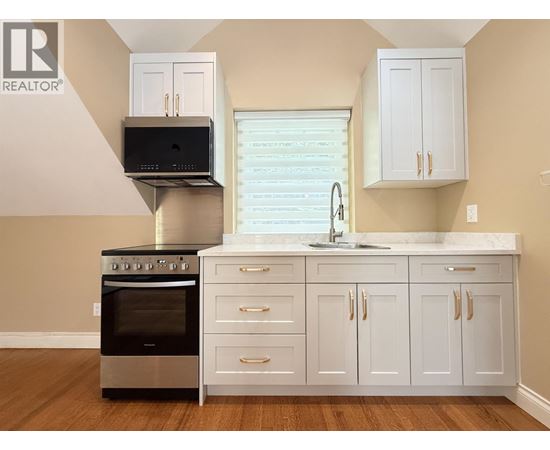 A modern kitchen with white cabinets and a stainless steel oven.