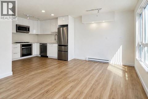 A spacious kitchen with wooden floors and stainless steel appliances.