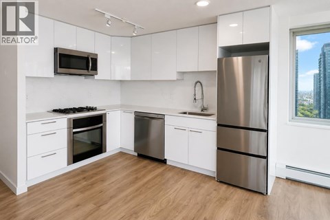 A modern kitchen with white cabinets and stainless steel appliances.