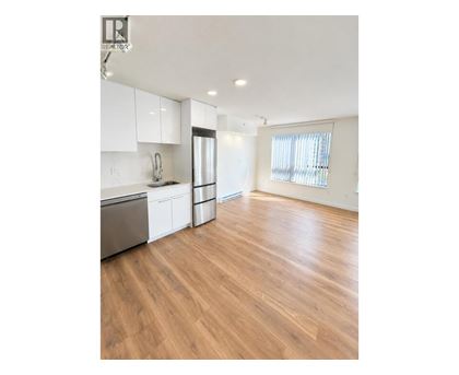 A kitchen with white cabinets and a wooden floor.