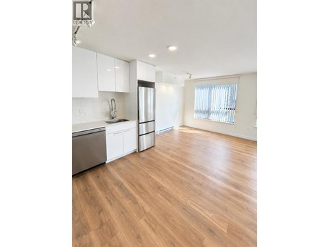 A kitchen with white cabinets and a wooden floor.