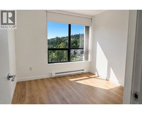 A room with a large window overlooking a forest.