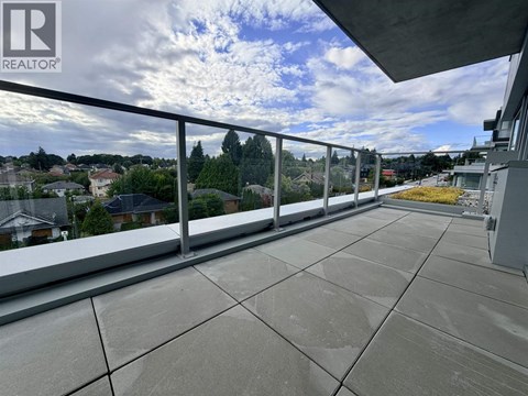 A balcony with a metal railing and a view of houses and trees.