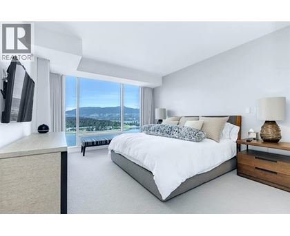 A bedroom with a large bed and a view of the mountains outside the window.