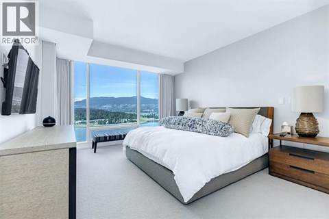 A bedroom with a large bed and a view of the mountains outside the window.