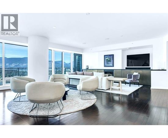 A living room with white furniture and a large window overlooking a snowy landscape.