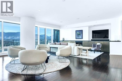A living room with white furniture and a large window overlooking a snowy landscape.