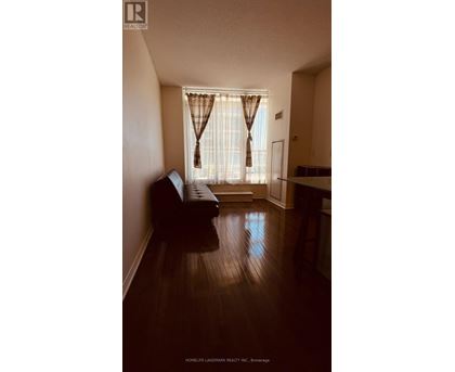 A living room with a brown couch and a window with curtains.