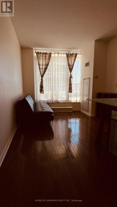 A living room with a brown couch and a window with curtains.